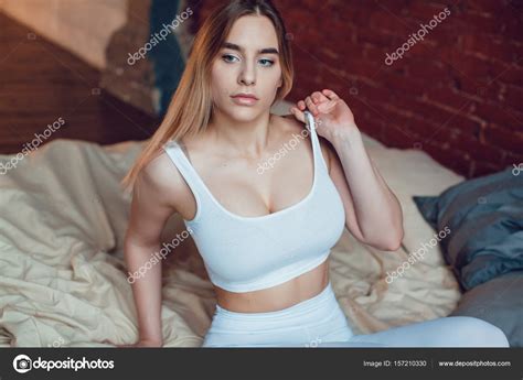 Sexy Blonde Woman With Huge Breast In A White Tank Top Sitting On A Bed Mock Up Stock Photo By