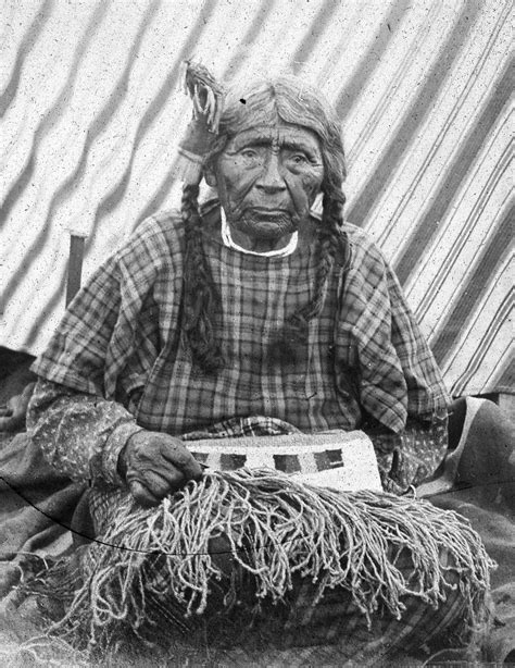An Old Native American Woman Sitting In Front Of A Tent
