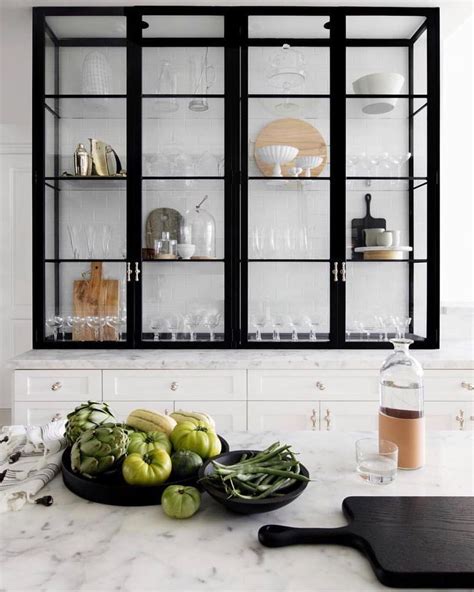 Thinking about adding glass cabinet doors in your kitchen? Kitchen with black metal and glass shelving + Marble ...