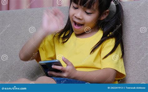 Cute Little Girl Taking A Selfie On Her Smartphone Sitting On The Sofa