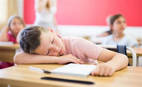 Tired School Boy Sleeping In Classroom During Lesson Stock Photo