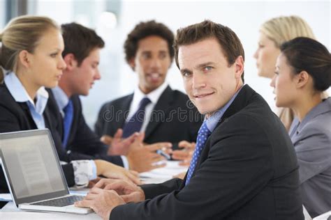 Portrait Of Male Executive With Office Meeting In Background Stock