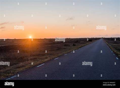 Sunrise By A Straight Country Road In A Great Plain Grassland At The