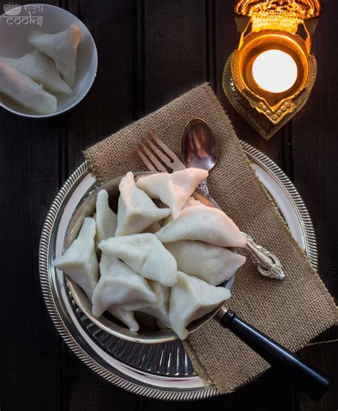 Some Dumplings Are On A Plate Next To A Candle And A Glass Bowl With