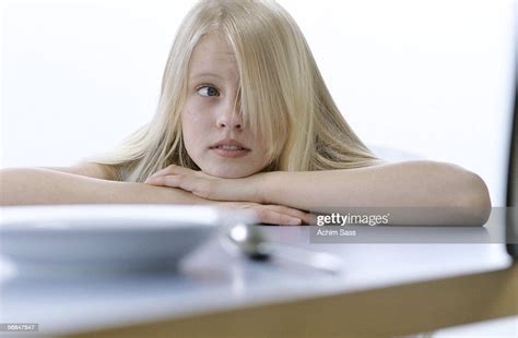 Girl At Table Resting Chin On Hands Looking Away Photo Getty Images