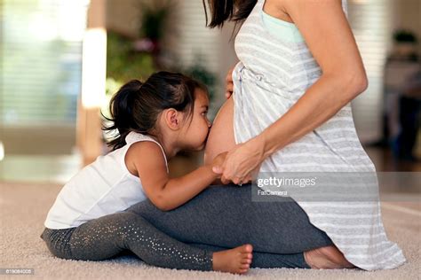 Cute Young Ethnic Girl Kissing Mommys Pregnant Belly High Res Stock