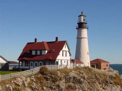 A Light House Sitting On Top Of A Rocky Cliff Next To The Ocean With A