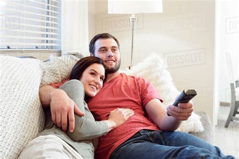 Caucasian Couple Cuddling On Sofa Watching Television Stock Photo Dissolve
