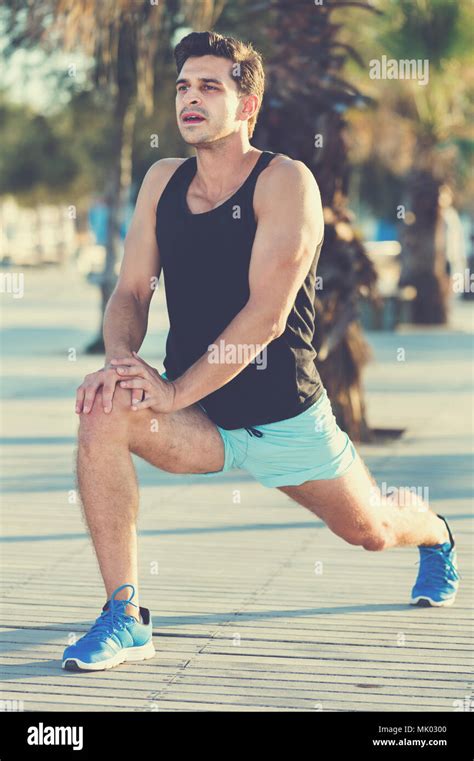 Physically Fit Cheerful Man Doing Stretching Exercises On Morning Beach