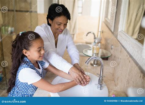 Grandmother And Granddaughter Washing Hands At Bathroom Sink Stock