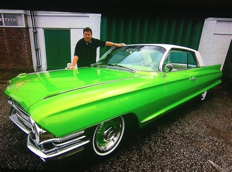 A Man Standing Next To A Green Classic Car