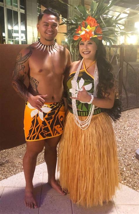 A Man And Woman In Hula Skirts Posing For A Photo With A Tiki Dancer