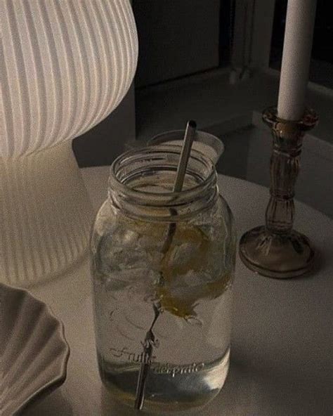 A Glass Jar Filled With Liquid Next To A Lit Candle And Some Shells On