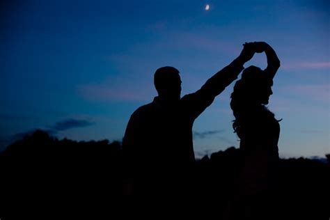 Two People Standing In The Dark With Their Arms Up And One Person