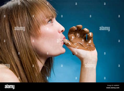 Woman Licking Melted Chocolate From Her Chocolate Covered Hand Stock