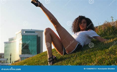 Attractive Skinny Mulatto Woman Lying On The Grass And Performing Strip Dance Elements Shifts