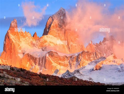 The Bright Red Peak Of Mount Fitzroy At Dawn Pink Clouds And Blue Sky