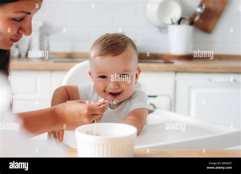 Charming Little Baby Boy Eating First Food Porridge From Spoon At The