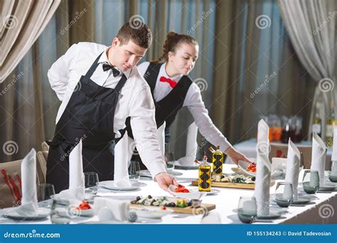 Waiters Serving Table In The Restaurant Preparing To Receive Guests