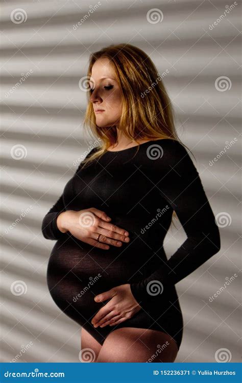 uma mulher gravida na roupa interior com uma barriga grande no nono mês da gravidez está