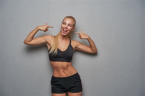 Enthousiaste Séduisante Jeune Femme Blonde Sportive Avec Une Coiffure Décontractée Pointant Vers