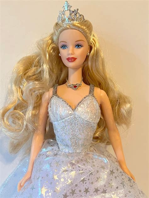 this is a vintage 2000 era beautiful barbie doll with blonde ringlets a silver star print dress