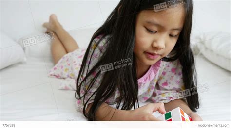 4k Video Little Asian Girls Playing Rubik Cube On The Bed Stock Video