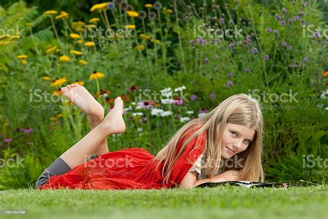Teenage Girl Lying On Grass And Reading A Magazine Stock Photo