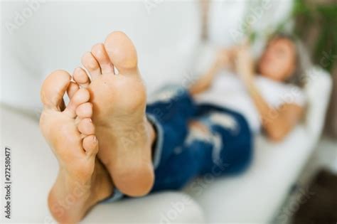 Bare Feet Of Woman In Jeans Using Smart Phonebare Foot Stock Photo
