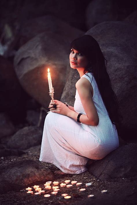 A Woman Sitting On Rocks Holding A Lit Candle