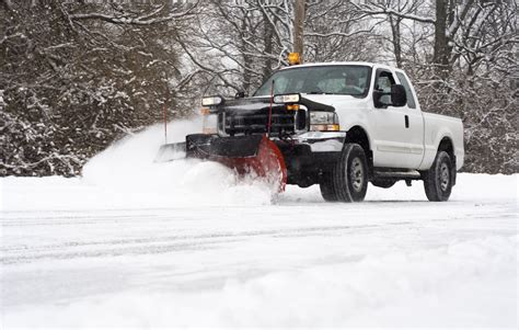 Man In Pickup Truck Plowing Road During Snow Storm Risingers Landscaping