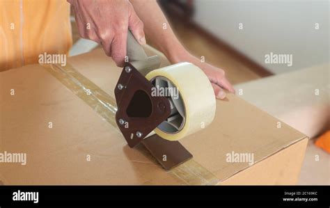 Close Up On A Womans Hands Closing A Cardboard Box With Adhesive Tape