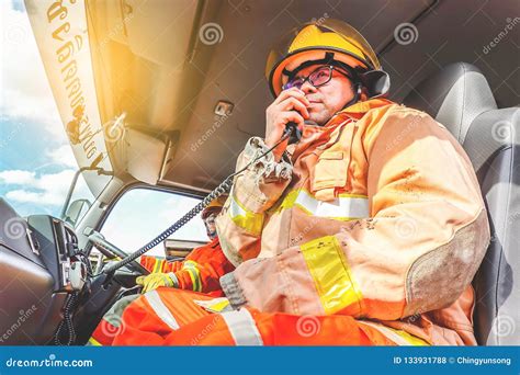 a firefighter in protective clothing and a helmet sits in a cargo rescue vehicle and talks on