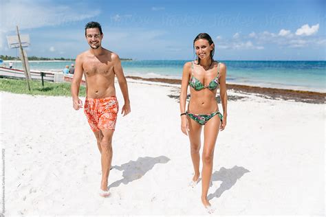 Young Couple Of Man And Woman Walking On The Sand Of A Tropical Beach On Vacation By Stocksy