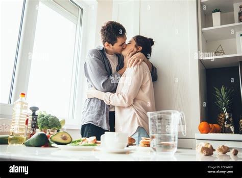 Caucasian Couple Kissing In The Kitchen While Preparing Food Near The