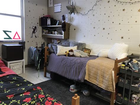 a dorm room with a bed desk and shelves on the wall next to it