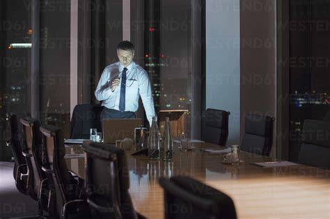 Businessman Working At Laptop In Conference Room At Night Stock Photo