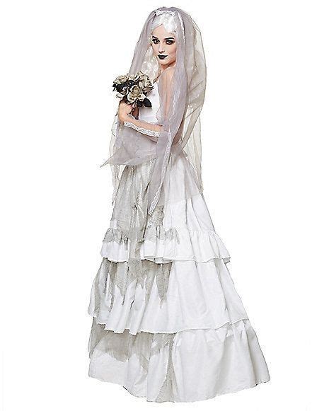 A Woman In A White Wedding Dress With Veil And Flowers On Her Head Holding A Bouquet