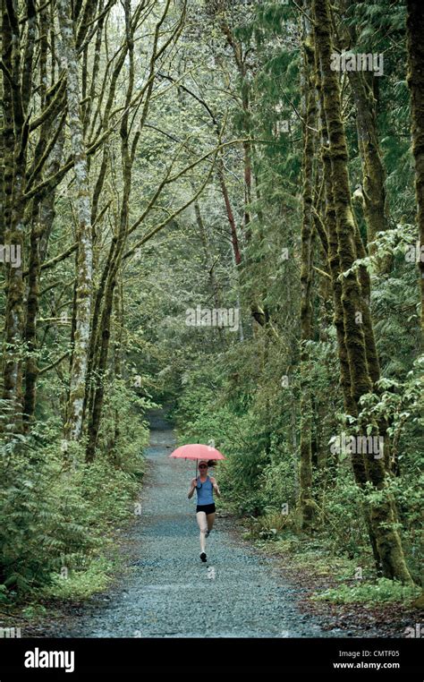 Mixed Race Runner Training On Remote Road With Umbrella Stock Photo Alamy