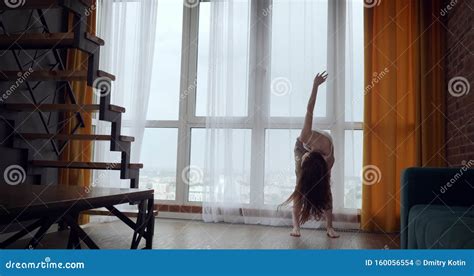 Young Woman Opens Curtains And Dancing Near Big Panoramic Window Stock