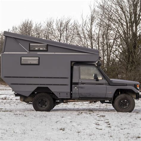 A Truck With A Camper Attached To It Parked In The Snow