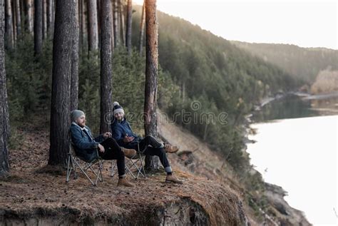 Men Sitting In Folding Chairs On Cliff By River Stock Image Image Of