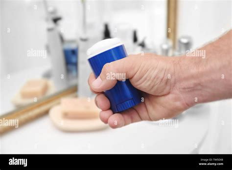 Man holding deodorant in bathroom Stock Photo - Alamy