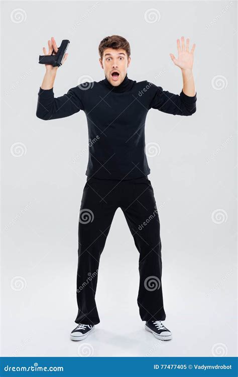 Scared Young Man Holding Gun And Standing With Hands Up Stock Image