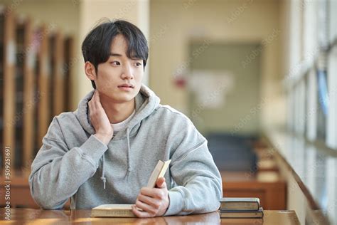 Foto Stock 아시아 한국의 대학교 도서관에서 다양한 자세로 책을 보고있는 젊은 대학생 남자 모델 Adobe Stock