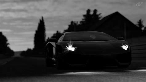 A Black And White Photo Of A Sports Car Driving Down The Road With