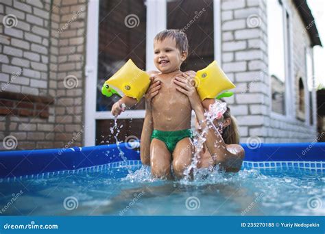 Mom Plays With A Naked Baby In Oversleeves In The Pool Against The