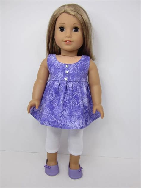 A Doll With Blonde Hair Wearing A Purple Dress And White Leggings
