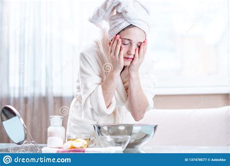Young Woman With A Towel On Her Head Washing Her Face With Water In The