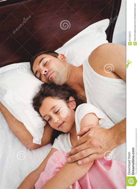Hija Que Duerme Al Lado De Padre En Cama En Casa Imagen De